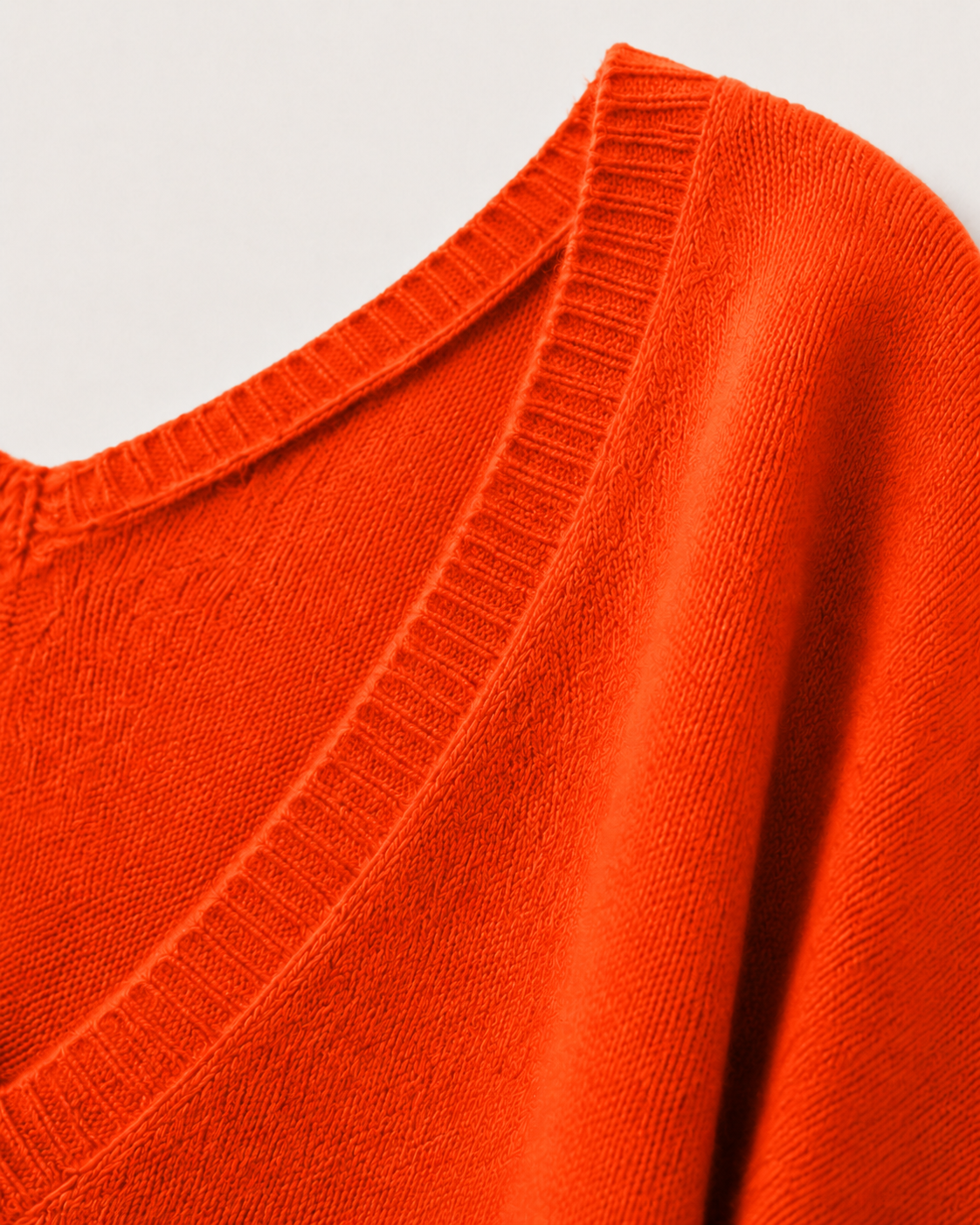 Dettaglio degli ampi scolli a V e del soffice filato in cashmere arancione