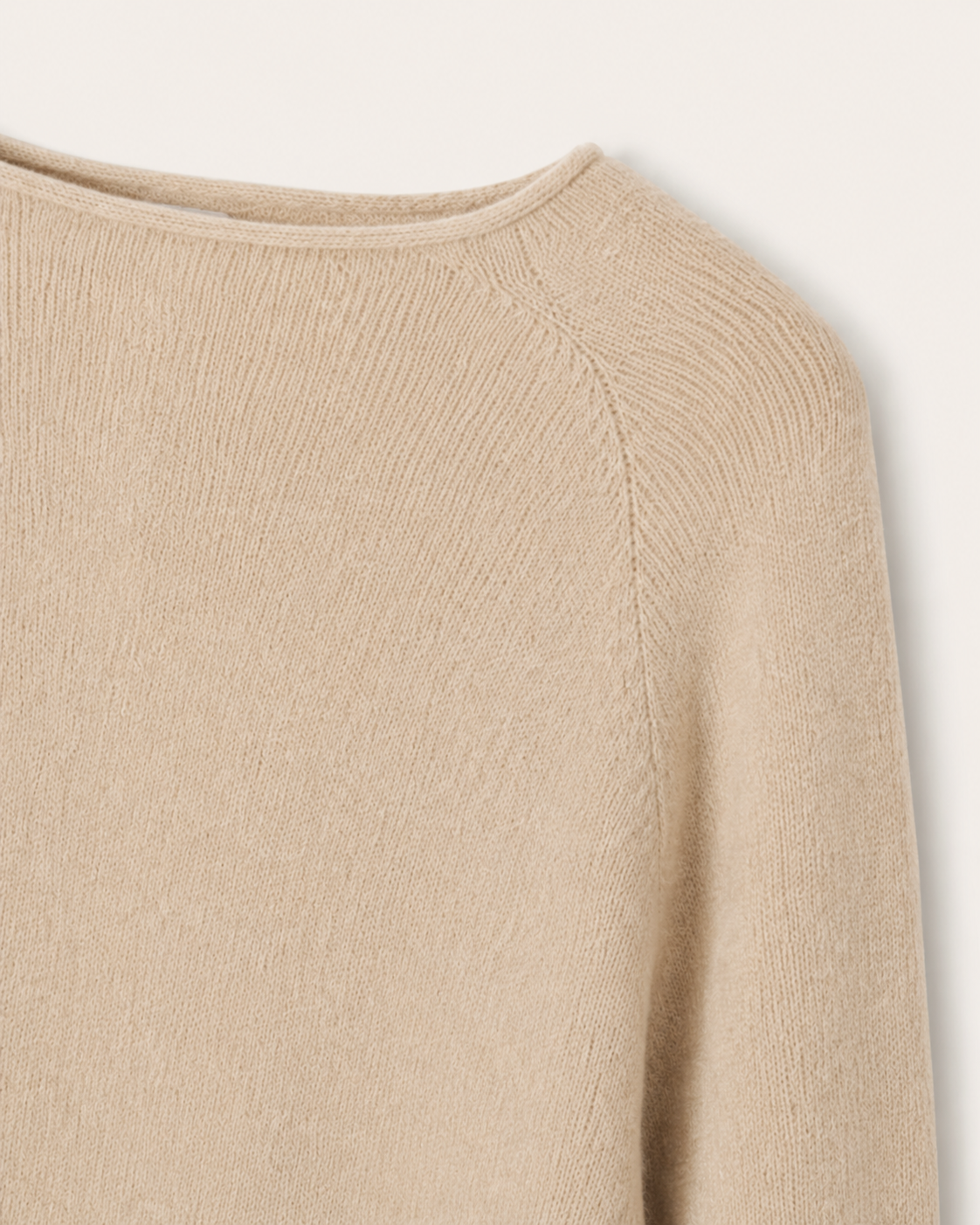 Dettaglio dello scollo a barchetta e della lavorazione raglan della cappa Cashmi beige in cashmere.