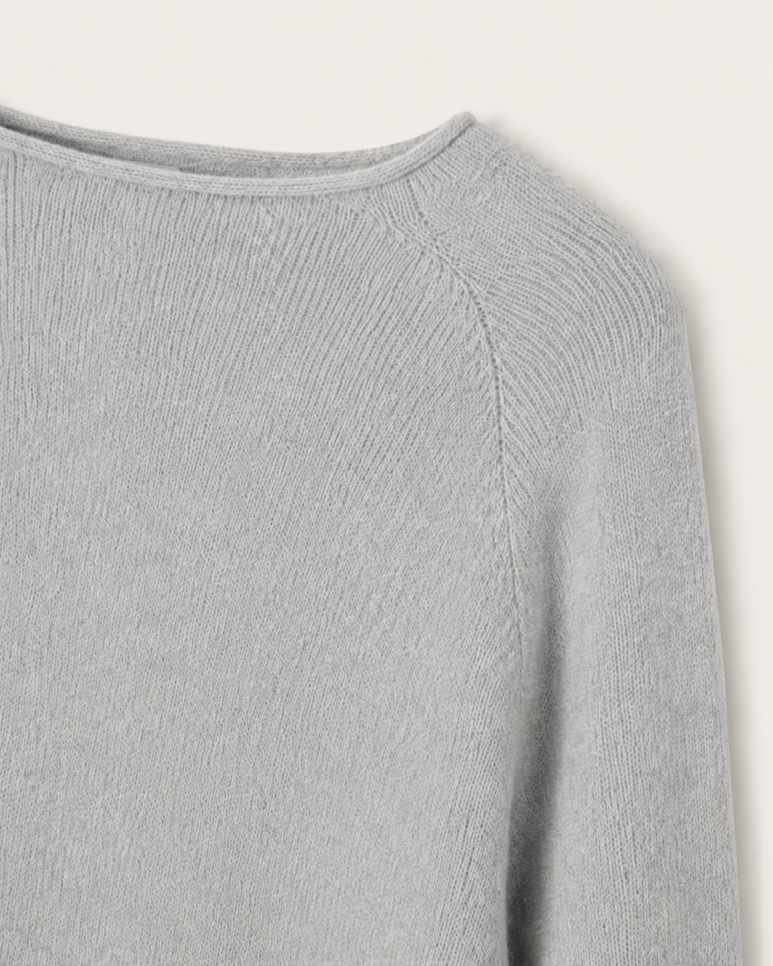 Dettaglio dello scollo a barchetta e della lavorazione raglan della cappa Cashmi grigia in cashmere.