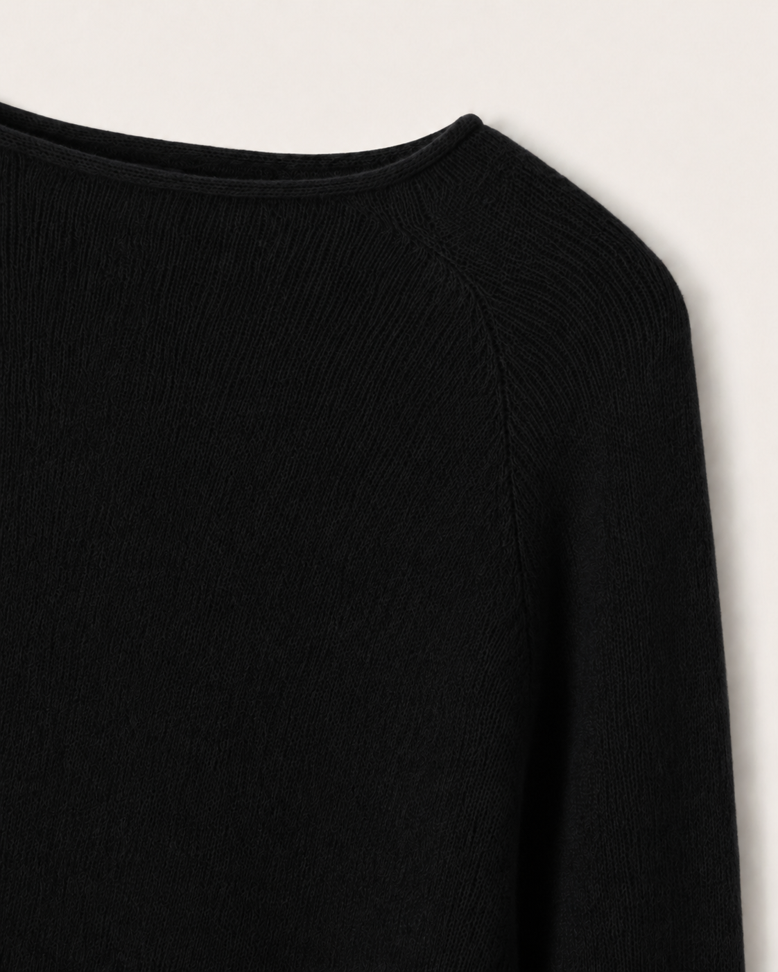 Dettaglio dello scollo a barchetta e della lavorazione raglan della cappa Cashmi nera in cashmere.