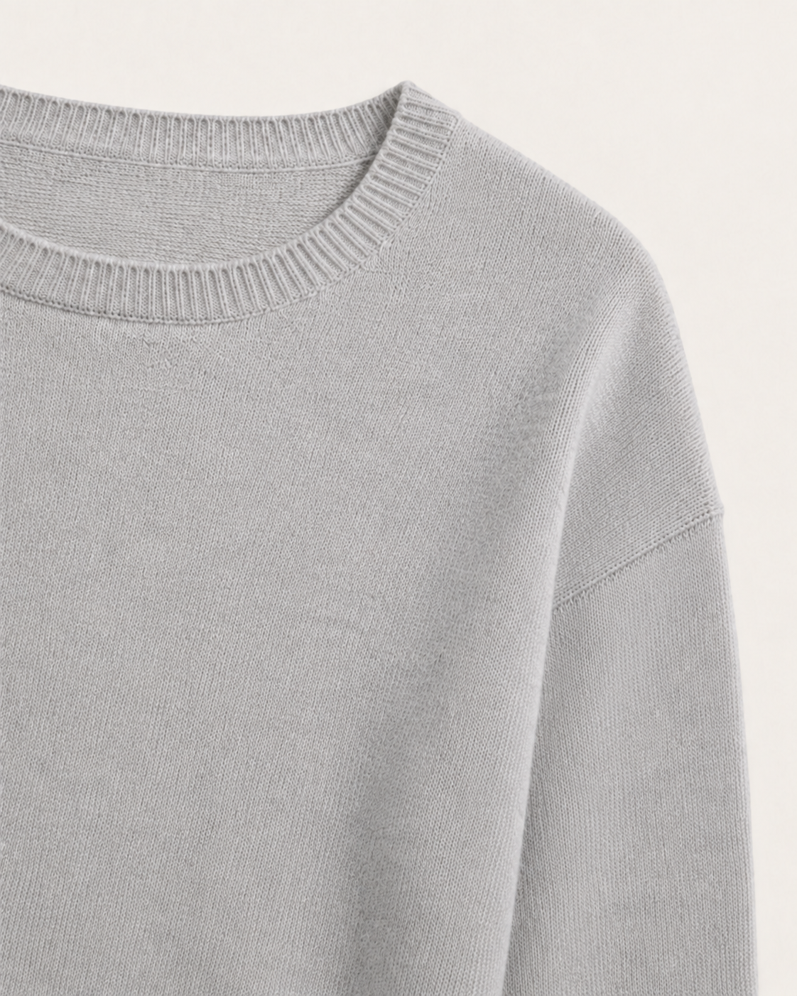 Dettaglio del girocollo e della spalla scesa del maglione Cashmi grigio chiaro mélange con maniche a tre quarti.