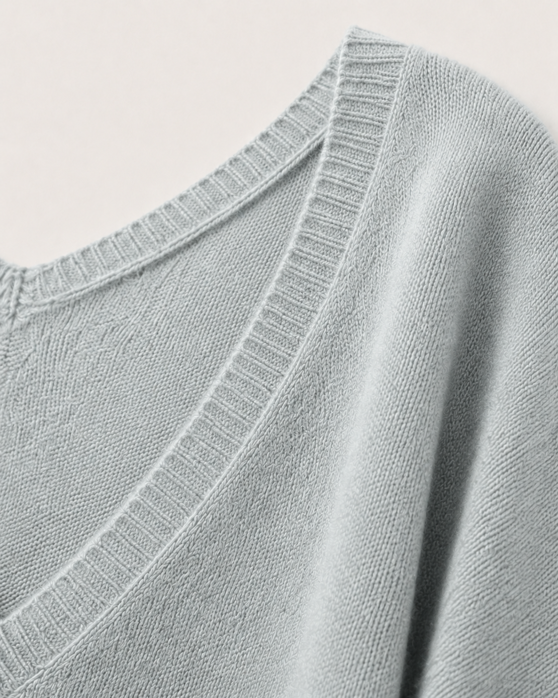 Dettaglio degli ampi scolli a V e del soffice filato in cashmere grigio chiaro