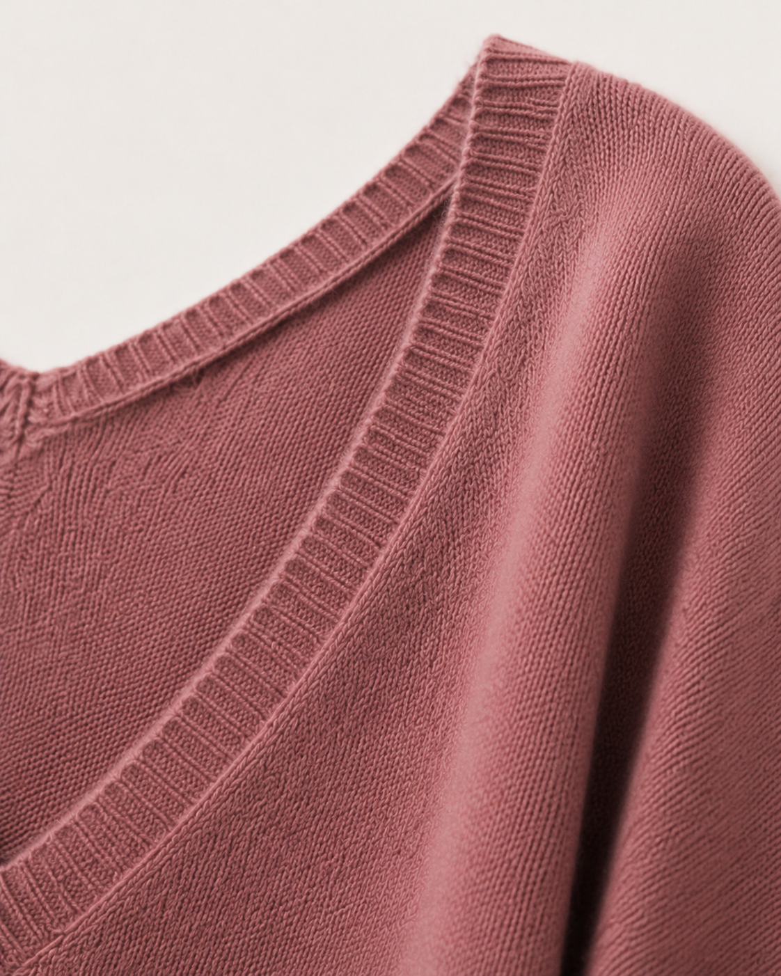 Dettaglio degli ampi scolli a V e del morbido filato in cashmere rosa